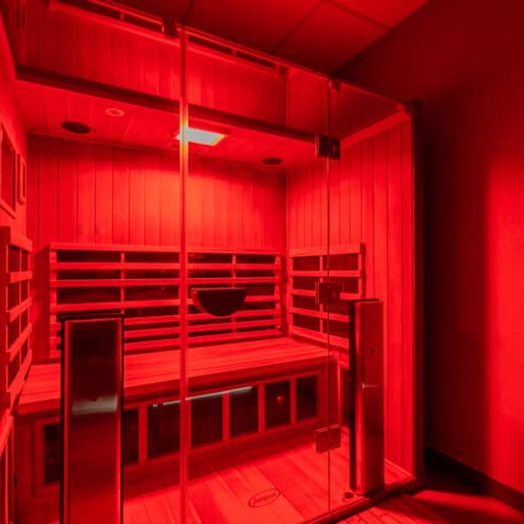 Interior of high-end infrared sauna at Legendary Recovery Miami, dark wood walls and warm ambient lighting